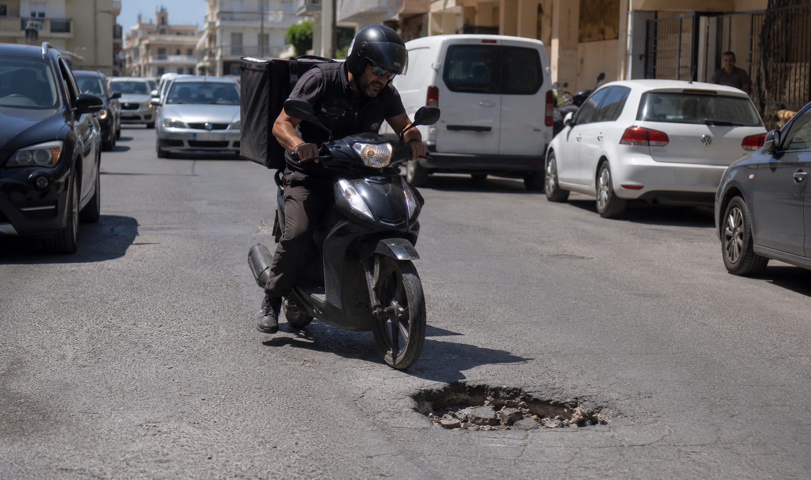 Διανομέας κινείται με μηχανάκι σε βρεγμένο δρόμο